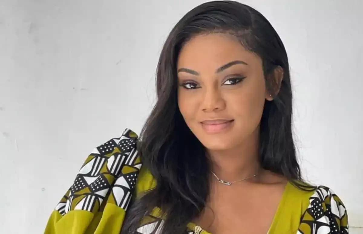 Portrait of Marie Paule Adjé, a woman with curly hair, smiling confidently against a neutral background.