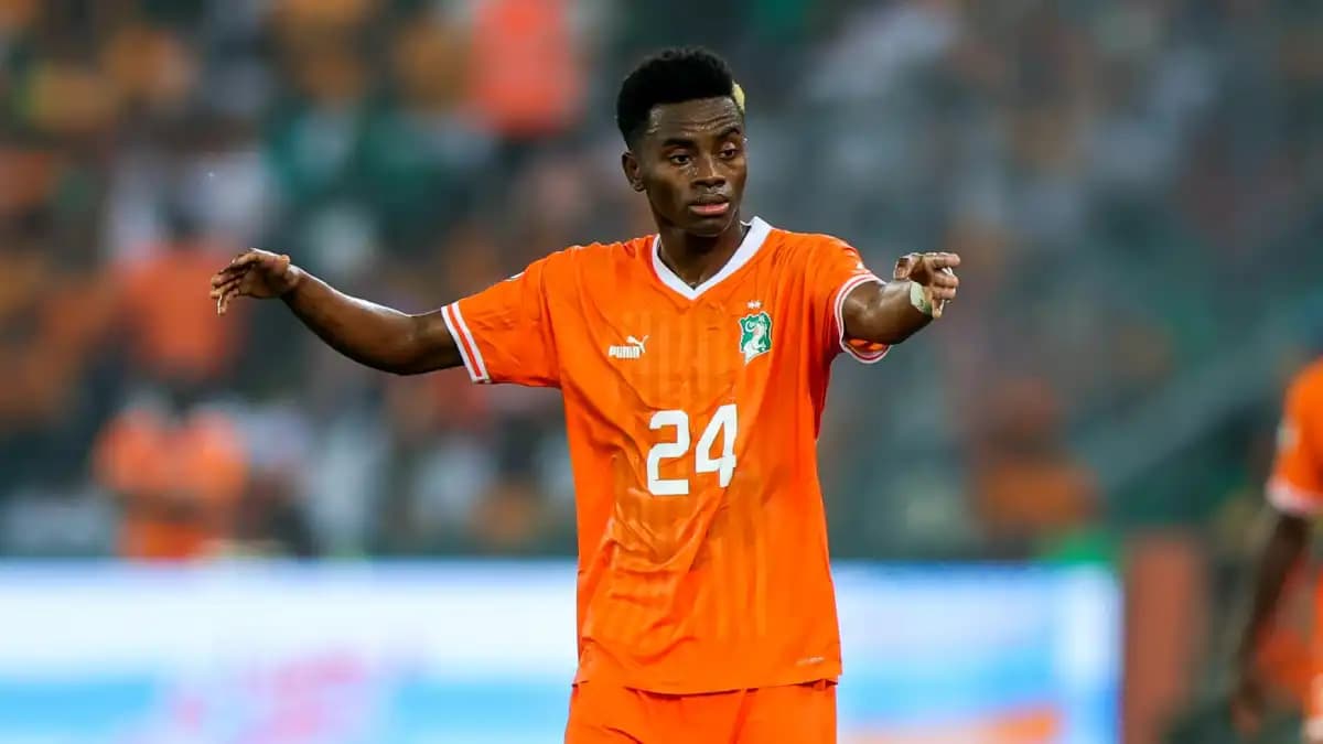 Simon Adingra in a soccer uniform, smiling on the field during a match.