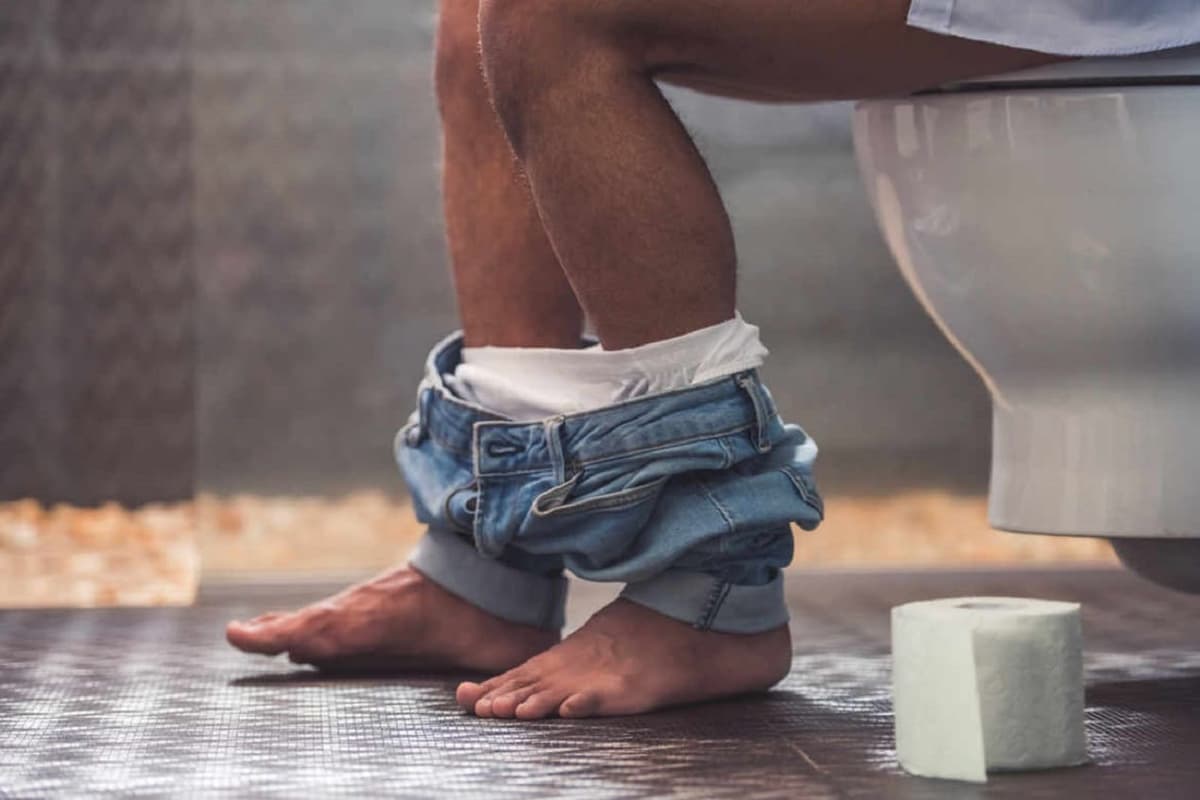 un pot de WC, papier hygiénique et une personne assise sur le pot