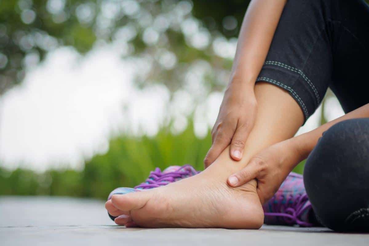 quelqu'un assise tenant sa cheville avec les deux mains