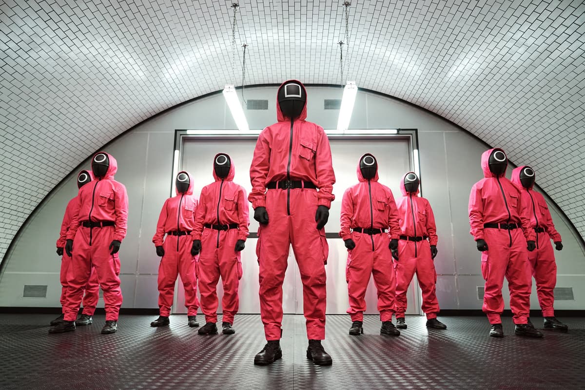 Logo de Squid Game avec des personnages emblématiques de la série sur fond coloré.