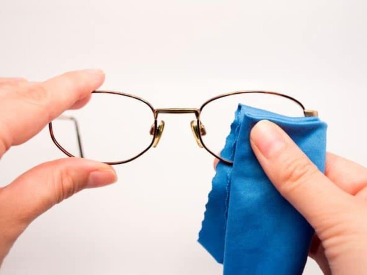 des mains en train de nettoyer une paire de lunettes