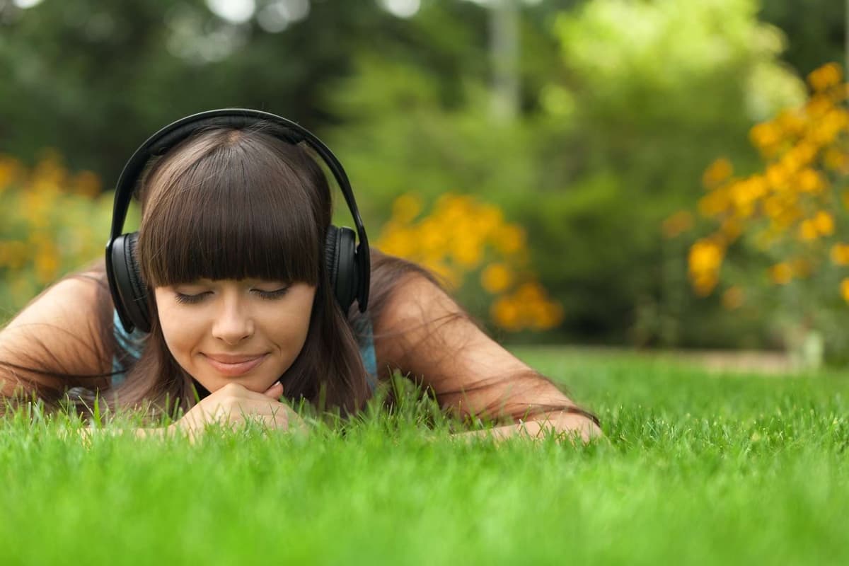 une personne avec des casques, couchée en train de savourer une bonne musique