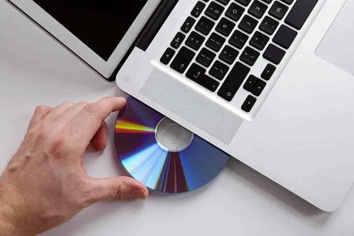 une main en train de retirer un CD d'un lecteur de PC