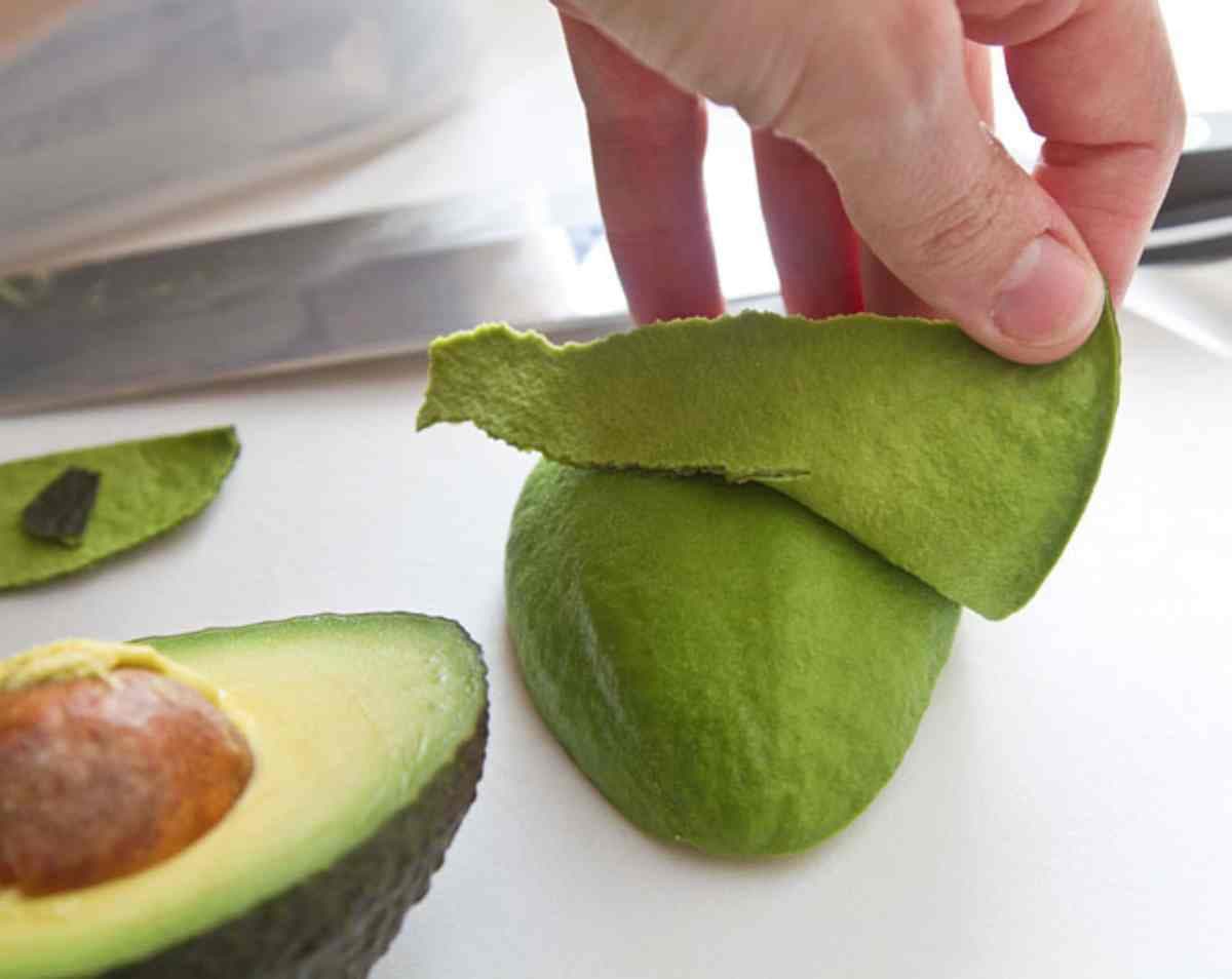 une main en train d'enlever les pelures d'avocat
