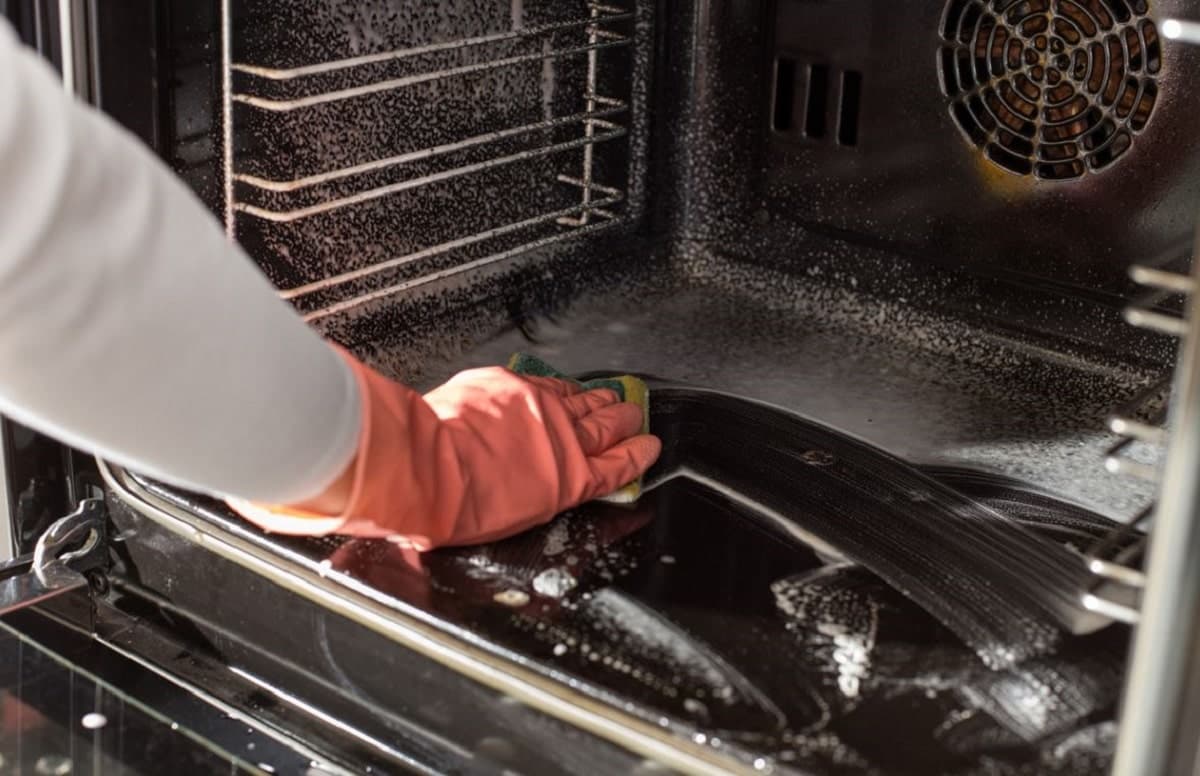 une main en train de nettoyer un four
