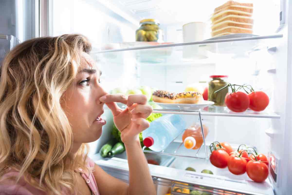 une femme en face d'un frigo se pincant les narines