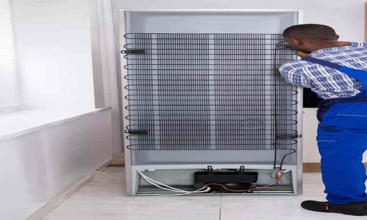 un homme entrain de nettoyer la grille du réfrigérateur