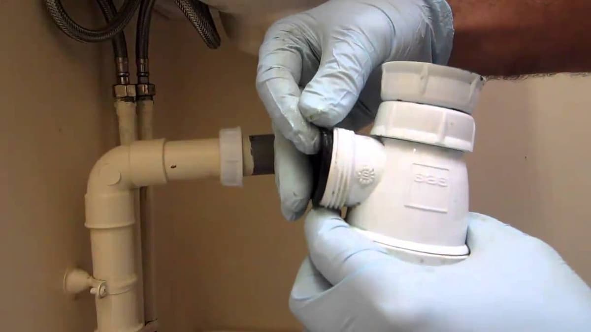 deux portant de gants entrain de travailler sur un siphon de lavabo