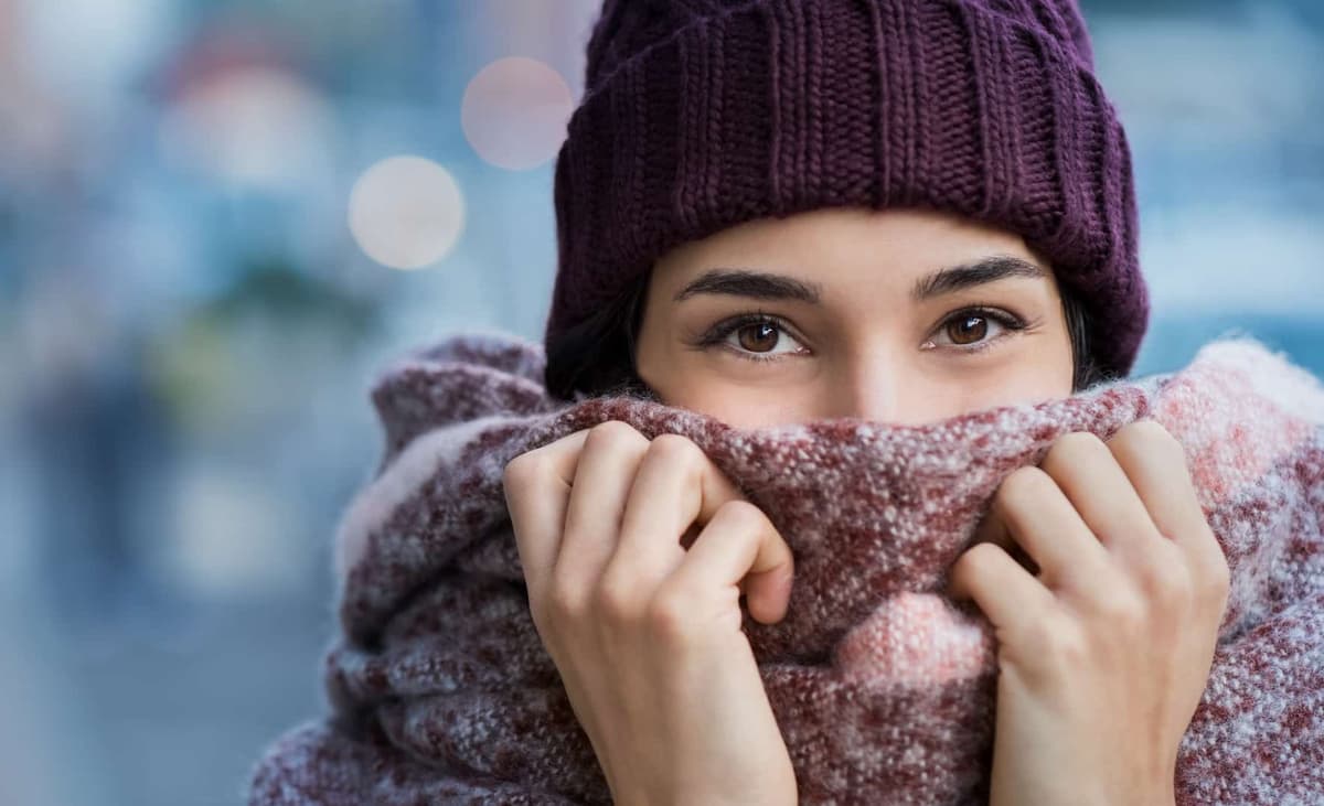 une personne ayant froid, se couvrant d'un bonnet, et d'une écharpe