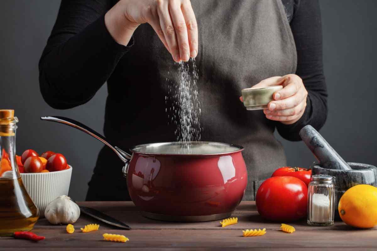 une femme en train de saler un repas dans une casserole rouge
