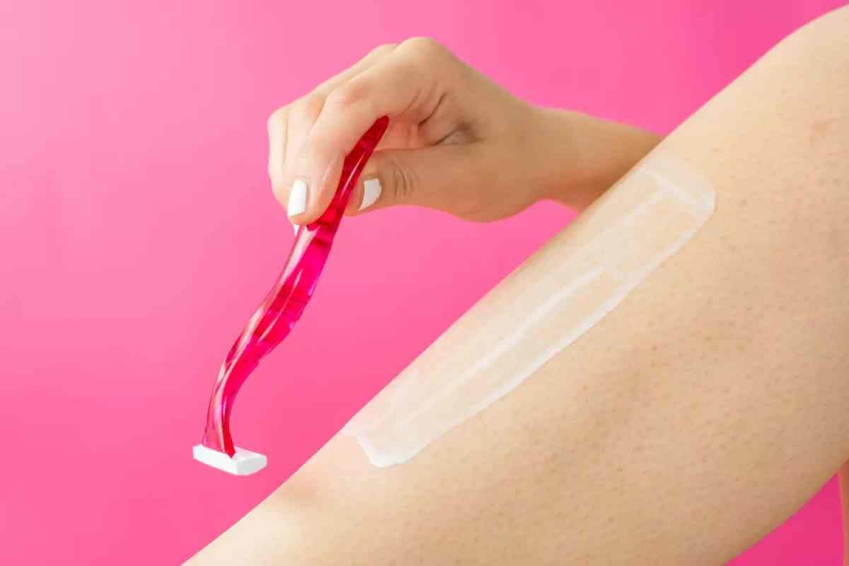 Une main rasant un pied avec un rasoir