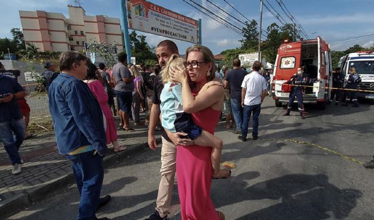 Femme portant un enfant en dehors d'une crèche où quatre enfants ont été tués à Blumenau, Brésil.