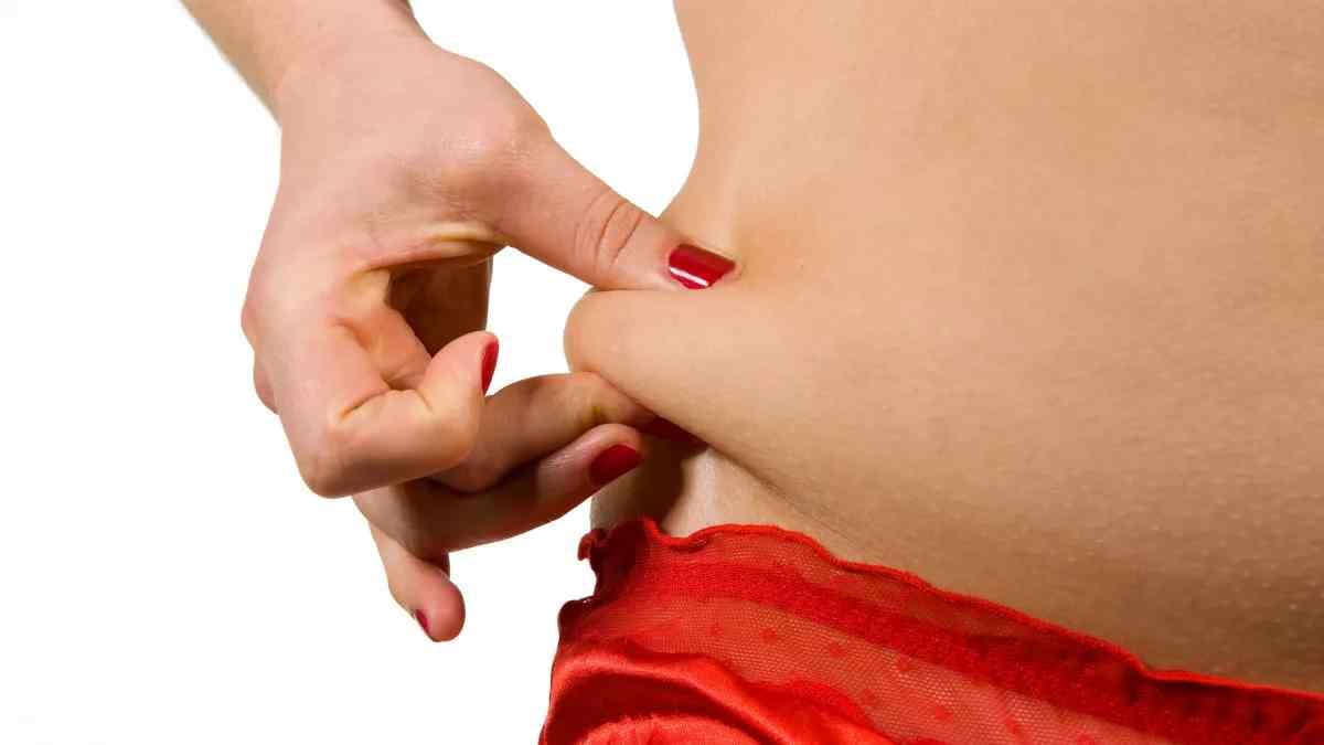 une personne se pinçant l'abdomen avec ls doigts