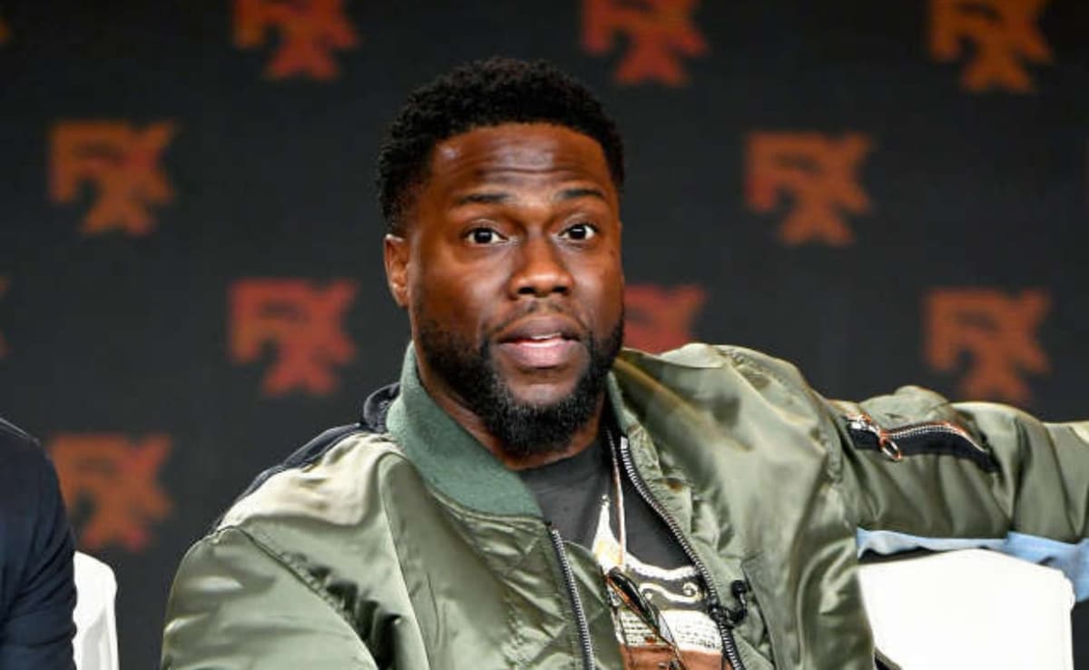 Kevin Hart en fauteuil roulant après une blessure, souriant et déterminé.
