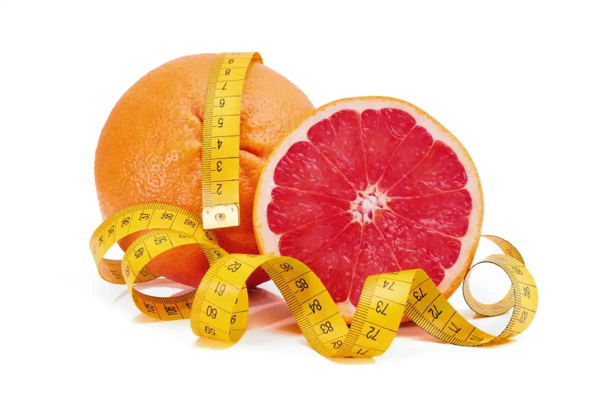 une orange coupée en deux avec un mètre