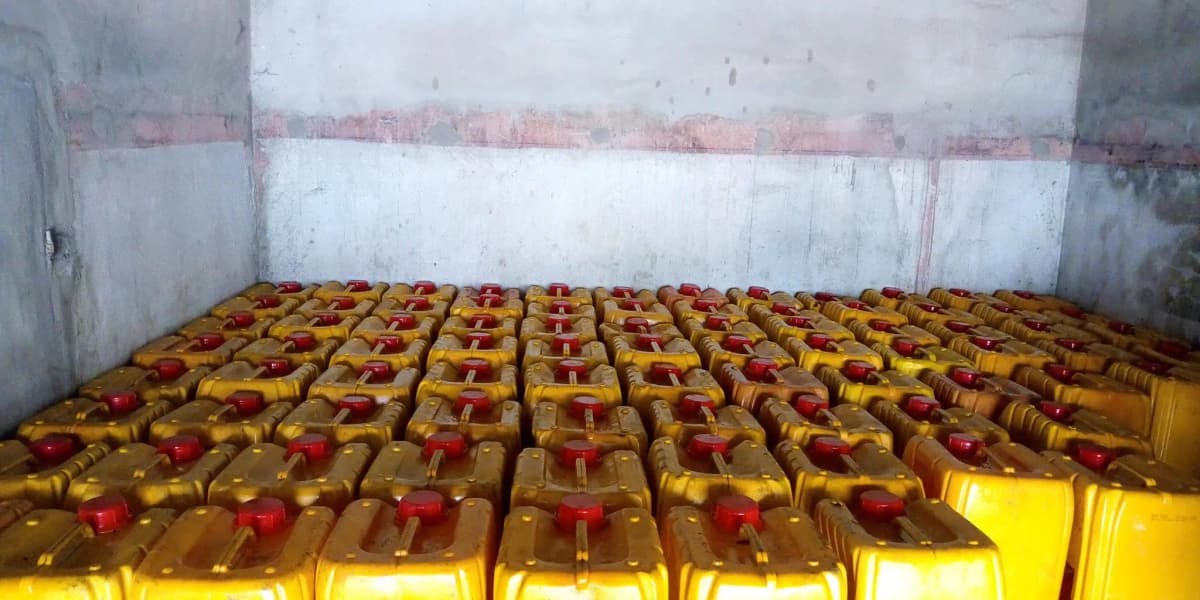 Bidons d'huile d'arachide sur une table, prix affiché en FCFA.