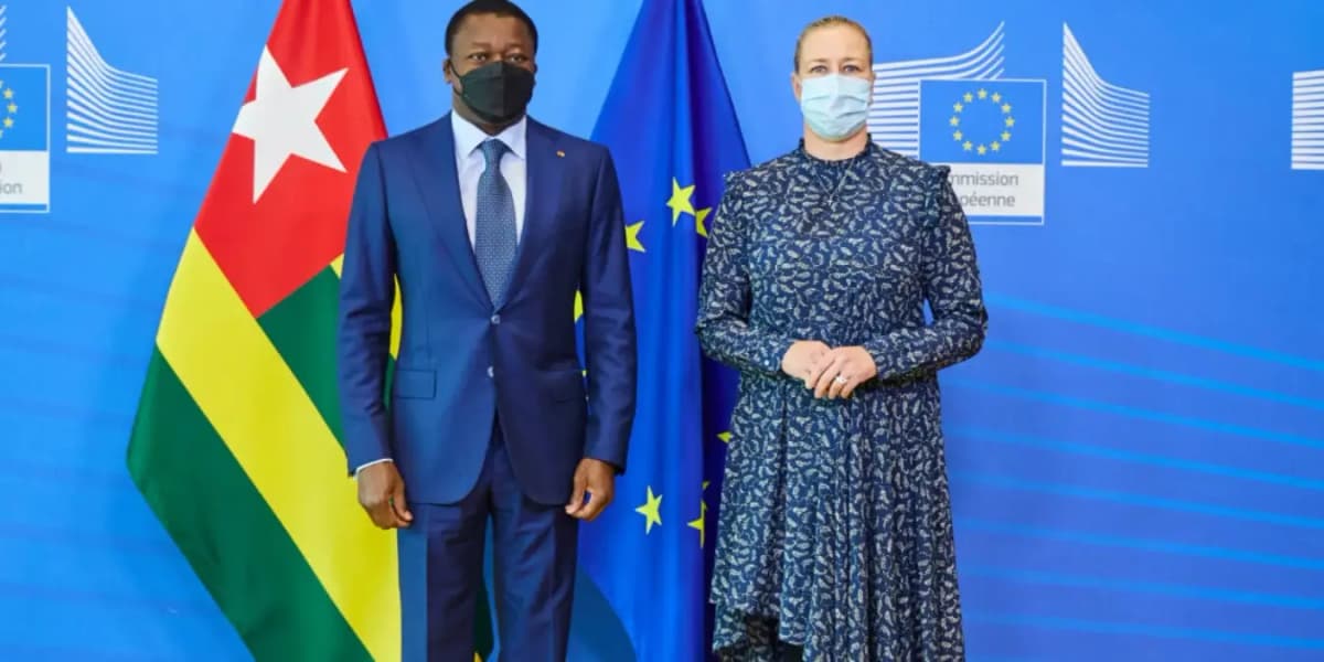 Logo de l'Union Européenne avec des drapeaux togolais en arrière-plan, symbolisant la coopération.