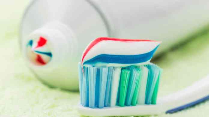 brosse à dent avec de la pâte dentifrice avec à côté un tube de pâte dentifrice