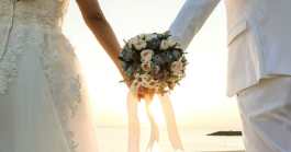 une femme en robe de mariée et un homme en costume se gardant la main avec un bouquet de fleur en main