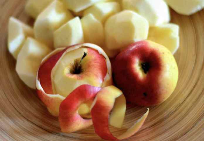 des pommes pelées et découpées, des pelures et une pomme non pelée