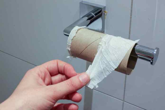 une main en train de toucher un rouleau de papier hygiénique vide