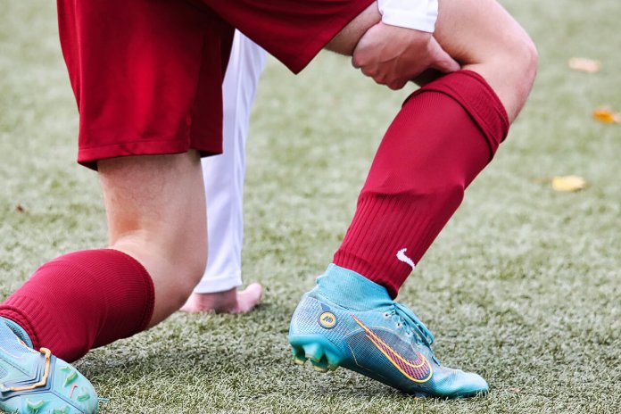 un joueur se tenant la cuisse suite à une blessure sur un terrain de football