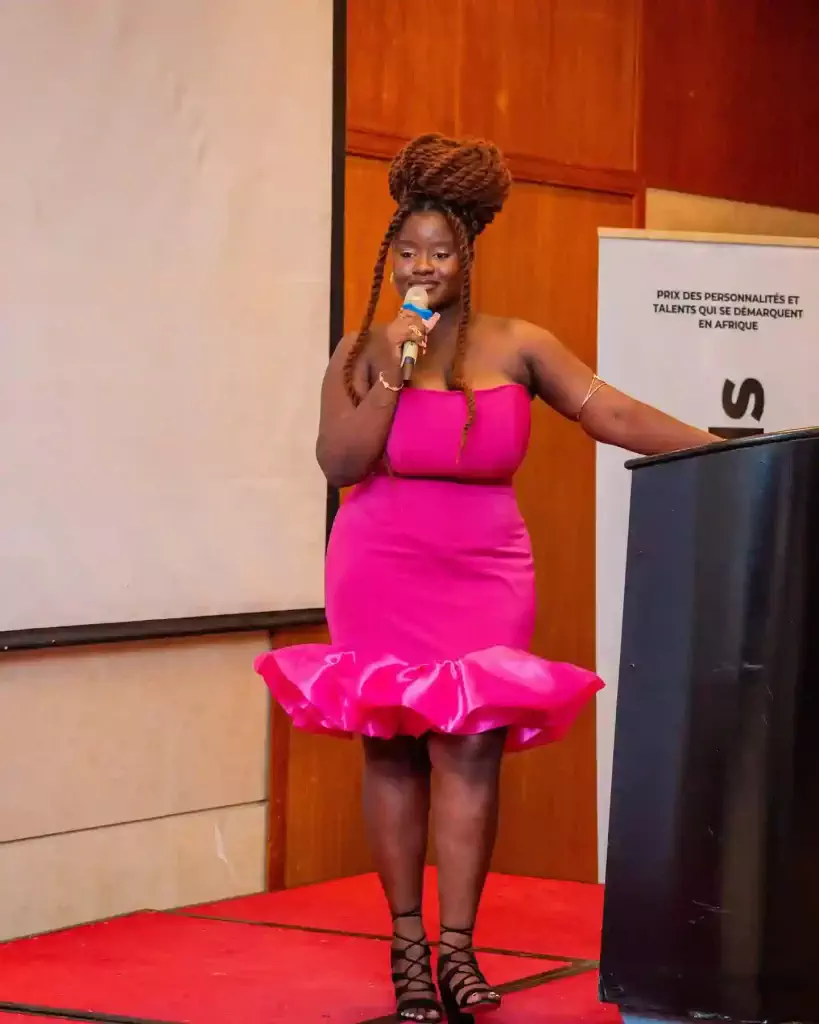 Légende: Valdye Gbaguidi, dans sa robe rose aux Opens Consciences 2024 en décembre 2024 où elle a été victime de body shaming et de sexualisation.